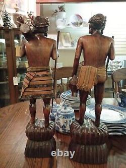 Paire de figurines en bois sculptées à la main de chasseurs de têtes nus tenant des parties