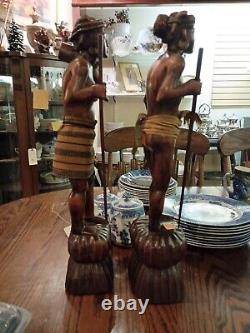 Paire de figurines en bois sculptées à la main de chasseurs de têtes nus tenant des parties