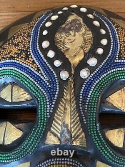 Paire de masques africains en bois sculpté, ronds, avec du laiton, des perles et des coquillages
