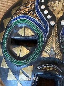 Paire de masques africains en bois sculpté, ronds, avec du laiton, des perles et des coquillages